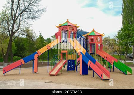 Terrain de jeu coloré pour enfants sur une cour de sable à proximité de beaux bâtiments. Banque D'Images