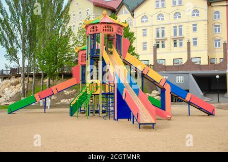 Terrain de jeu coloré pour enfants sur une cour de sable à proximité de beaux bâtiments. Banque D'Images