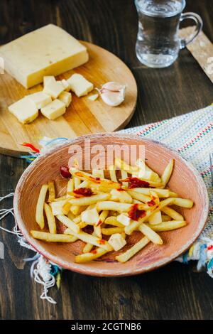 Frites de la poutine sur la surface noire. Plat canadien avec pommes de terre, fromage et sauce Banque D'Images