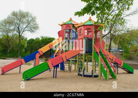 Terrain de jeu coloré pour enfants sur une cour de sable à proximité de beaux bâtiments. Banque D'Images