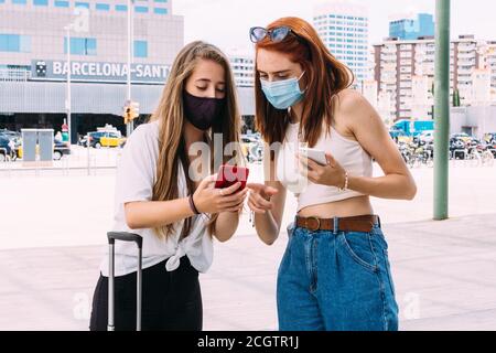 deux jeunes touristes avec un masque de visage recherchent le adresse à l'hôtel sur leur smartphone Banque D'Images