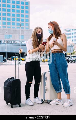 deux jeunes touristes avec un masque de visage recherchent le adresse à l'hôtel sur leur smartphone Banque D'Images