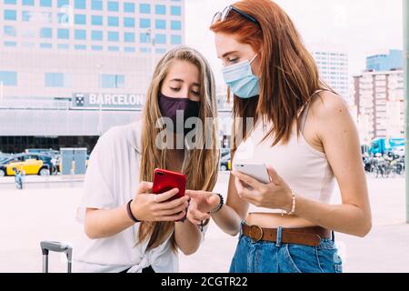 deux jeunes touristes avec un masque de visage recherchent le adresse à l'hôtel sur leur smartphone Banque D'Images