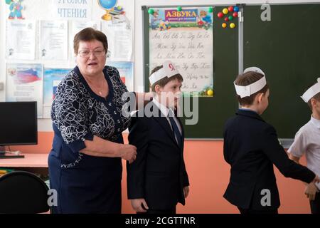 Un enseignant avec des garçons de premier cycle se tient devant un tableau noir dans la salle de classe pendant les vacances d'adieu à l'ABC. Banque D'Images