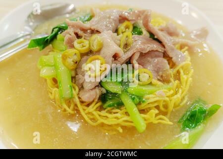 Nouilles dans un bol avec légumes et porc sur fond flou, style asiatique de vie de nouilles, savoureuses nouilles asiatiques Banque D'Images