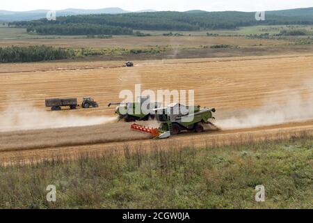 Les moissonneuses-batteuses ramassant le chaume à côté du tracteur sur le terrain pendant la campagne de récolte. Banque D'Images