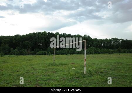 Terrain de football rural avec vide et rouillé dans le but post premier plan et forêt en arrière-plan Banque D'Images