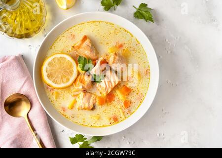 Une assiette avec une délicieuse soupe de saumon à la crème végétalienne, aux carottes et aux pommes de terre sur fond blanc. Gros plan Banque D'Images