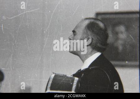 Belle photo en noir et blanc vintage des années 70 d'un musicien jouant de l'accordéon. Banque D'Images