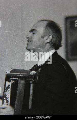 Belle photo en noir et blanc vintage des années 70 d'un musicien jouant de l'accordéon. Banque D'Images