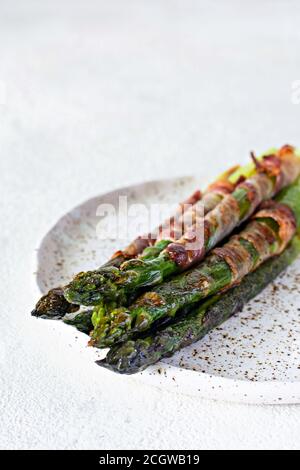 Asperges cuites au four mûr avec bacon, accompagnement pour le petit déjeuner, déjeuner, barbecue. Banque D'Images