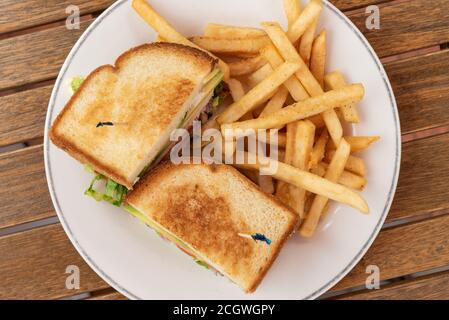 Le Club sandwich et les frites sur une assiette font un délicieux repas quand il a faim. Banque D'Images