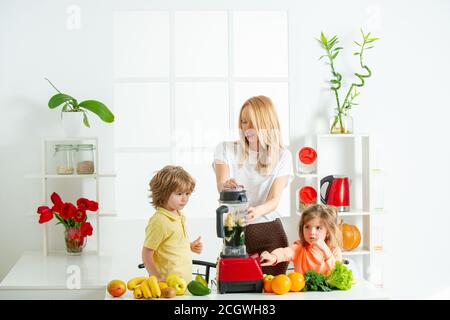 Concept de famille Superfood. Bonne famille aimante. Maman fille et fils préparent un smoothie dans la cuisine. Amusez-vous et jouez avec les légumes. Une alimentation saine Banque D'Images