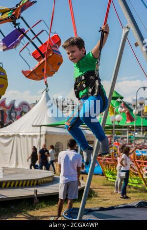 Un petit garçon rebondit en plein air à l'aide d'un trampoline à élastique. Banque D'Images