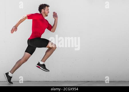 Homme de course entraînement de coureur faire des courses de ville en plein air sprint le long de fond de mur. Vie urbaine saine et active. Athlète masculin faisant sprint hiit Banque D'Images