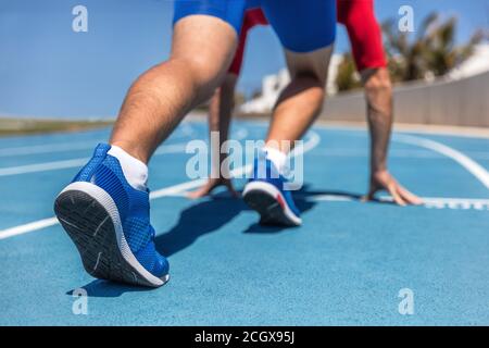 Sprinter attendant le début de la course sur les pistes de course au stade en plein air. Sport et forme physique coureur homme athlète sur piste bleue avec des chaussures de course à pied. Banque D'Images