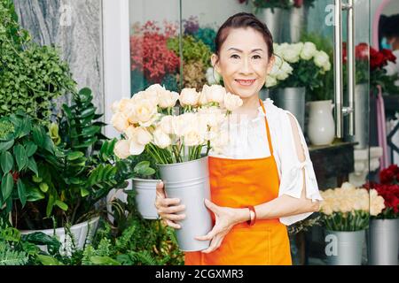 Fleuriste senior avec seau de roses fraîches Banque D'Images
