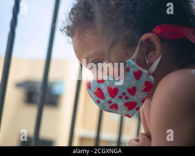 Une petite fille avec un masque de coeur est à la recherche extérieur Banque D'Images