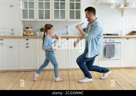 Adorable enfant chantant la chanson préférée avec un jeune père amusant. Banque D'Images