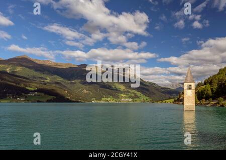 Le sommet de l'ancien clocher de Curon (Graun) émerge des eaux du lac Resia, contre un ciel spectaculaire, au Tyrol du Sud, en Italie Banque D'Images