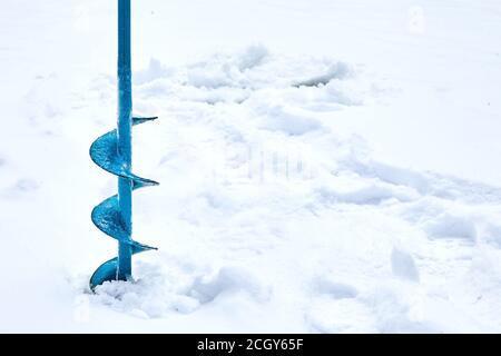 Tarière à glace manuelle utilisée pour la pêche sous la glace. Vis métallique bleue. Percer. Passe-temps, pêche d'hiver sur le lac enneigé Banque D'Images