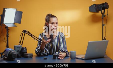 Video Blogger faisant une comparaison de produit entre deux types de batteries NP-F. Créateur de contenu nouveau Media star influenceur sur les médias sociaux parler matériel vidéo professionnel de photo pour le Web en ligne de spectacle Banque D'Images