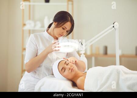 Jeune femme détendue bénéficiant de procédures de soin de la peau professionnelles dans la beauté moderne salon Banque D'Images