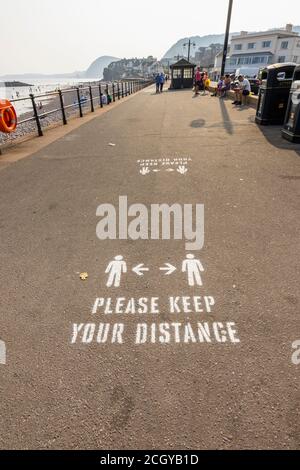 Instructions, veuillez garder votre distance, peint sur le pavé de la promenade du front de mer à Sidmouth, une ville côtière de Devon sur la côte sud Banque D'Images