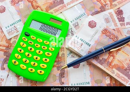 Le numéro 1,000,000 est écrit sur la calculatrice, la calculatrice et le stylo à bille reposent sur un tas d'argent Banque D'Images