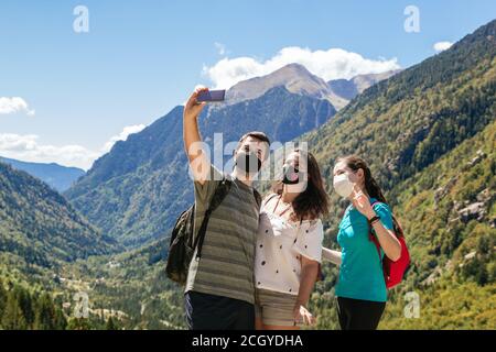 Photo d'un groupe de trois amis portant un masque et prendre un selfie tout en appréciant les montagnes et la beauté décor Banque D'Images