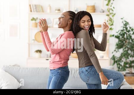 Joyeux copines noires chantant et dansant à la maison Banque D'Images