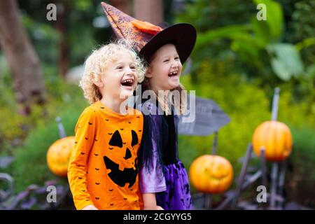 Enfant en costume d'Halloween. Les enfants font des trucs ou des friandises. Petit garçon et fille vêtu de sorcière avec chapeau tenant lanterne de citrouille et seau de bonbons. Célébrité de la famille Banque D'Images