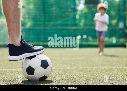 Joueur qui marche sur le ballon de football debout sur un terrain vert Banque D'Images