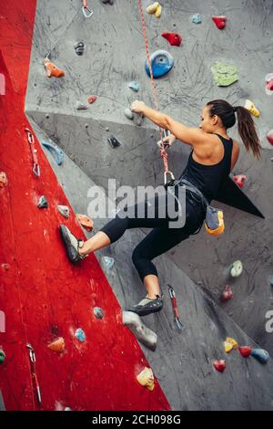 Succès sportif business woman étant occupé à son passe-temps-bloc. Femme bien équipée de la formation dans une salle d'escalade de couleur, la préparation à l'été, moun Banque D'Images