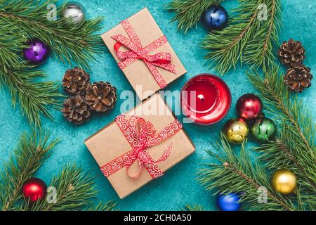 Fond de Noël avec boules, boîte cadeau, bougie rouge et branches de pin, carte de vœux de Noël lumineuse, composition plate festive du nouvel an sur turquoise Banque D'Images