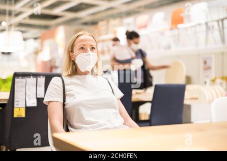 Nouvelle normale pendant l'épidémie de covid. Femme caucasienne magasiner au magasin de meubles et d'accessoires à la maison portant masque médical de protection pour le visage Banque D'Images