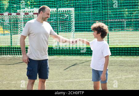 Homme donnant le poing de la bosse au terrain de football de garçon ar Banque D'Images