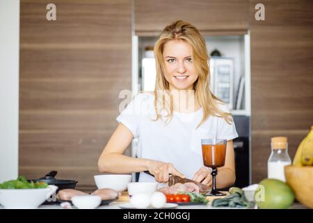 Woman slicing préparer la viande viande kebab sur une table de cuisine avec un grand couteau Chef. Cook attrayant couper la viande sur la table se prépare à surprendre son boyfr Banque D'Images