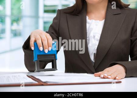 Femme d'affaires commis mettant le timbre sur les documents dans le bureau, concept de bureau Banque D'Images