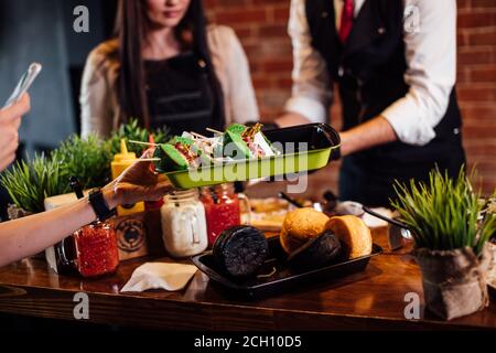 Premier plan de la salver Waitres avec des hamburgers verts fraîchement préparés, une commande étant prise de la cuisine de hamburger aux clients pendant le burgerfest Banque D'Images