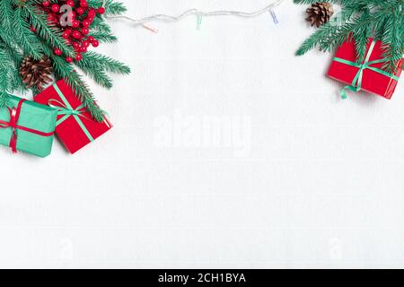 Composition de Noël. Cadeaux de Noël, branches de pin, lumière de noël, guirlande sur fond blanc. Vue du dessus. Banque D'Images
