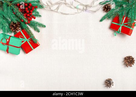 Cadre de Noël en branches de sapin, baies de houx rouges, cadeaux de Noël, papier peint de Noël. Flat lay, vue de dessus, espace de copie. Banque D'Images