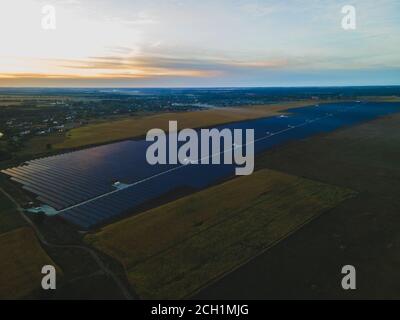 Vue aérienne de drone dans de grands panneaux solaires dans une ferme solaire dans un grand champ sur la campagne au coucher du soleil clair. Centrales solaires, photo colorée Banque D'Images