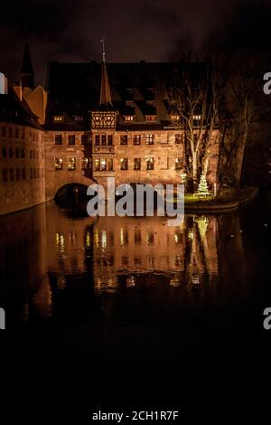 Vue en soirée de l'hôpital du Saint-Esprit (Heilig-Geist-Spital) qui est maintenant un restaurant, réfléchissant sur la rivière Pegnitz à Nuremberg, en Allemagne Banque D'Images