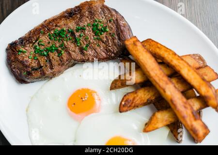 Photo de steak grillé avec grosses pommes de terre et œuf frit Sur une plaque Banque D'Images