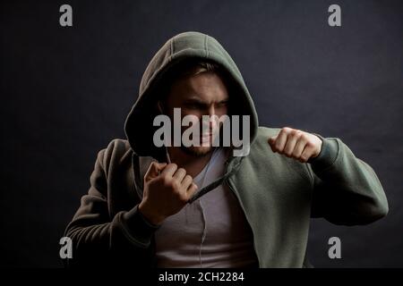 un jeune homme sérieux se bat avec des poings. prêt à attaquer. boxer dans le pull à capuche vert est frappant Banque D'Images