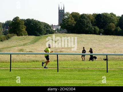 Un coureur et des randonneurs pendant la pandémie Covid-19 à l'hippodrome de Warwick, Warwickshire, Angleterre, Royaume-Uni Banque D'Images