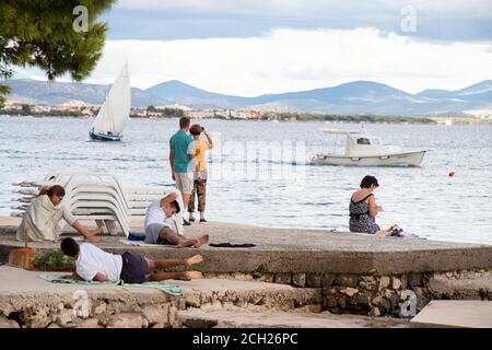 Vodice, Croatie - 1er septembre 2020 : les gens se détendent sur la plage en basse saison et les bateaux en mer Banque D'Images