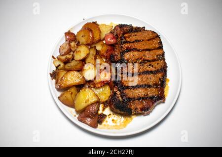 Un steak parfaitement grillé avec des lignes de grillades noires et des pommes de terre Plaqué sur un arrière-plan blanc pur Banque D'Images