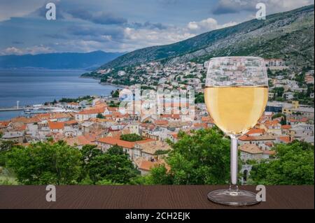 Verre de vin blanc contre vue d'en haut sur la ville de Senj, Croatie. Vue depuis la forteresse de Nehaj, fort sur la colline, Velebit, Croatie. Banque D'Images